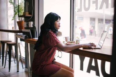 woman in red dress using laptop on table