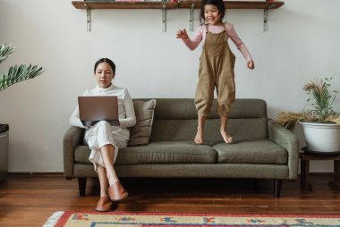 focused mother working on laptop near disturbing daughter